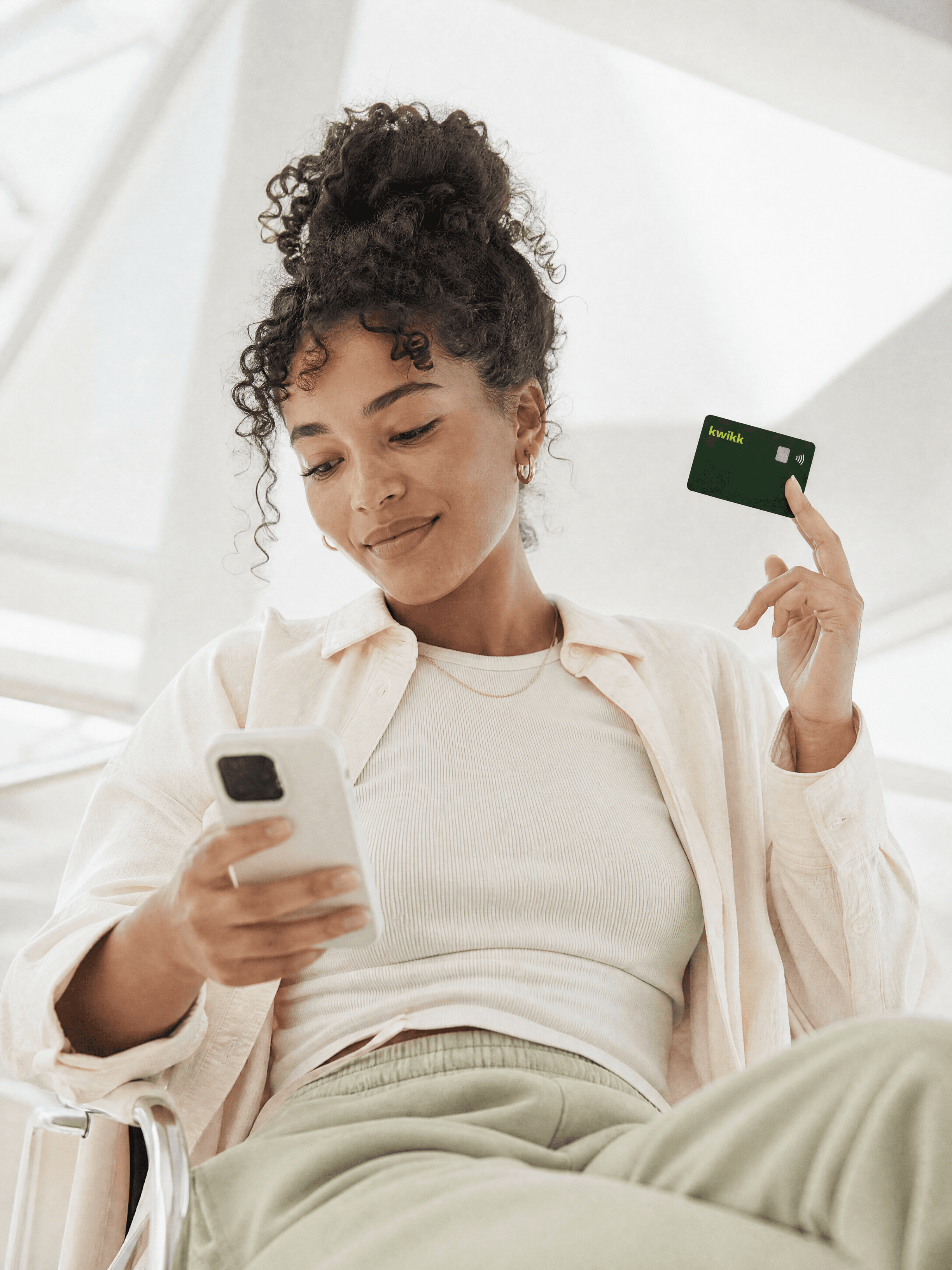 Meisje houdt haar donkergroene kwikk-kaart omhoog terwijl ze op haar telefoon kijkt
